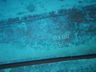 Large section of hull in debris field with "08KO" painted on plating